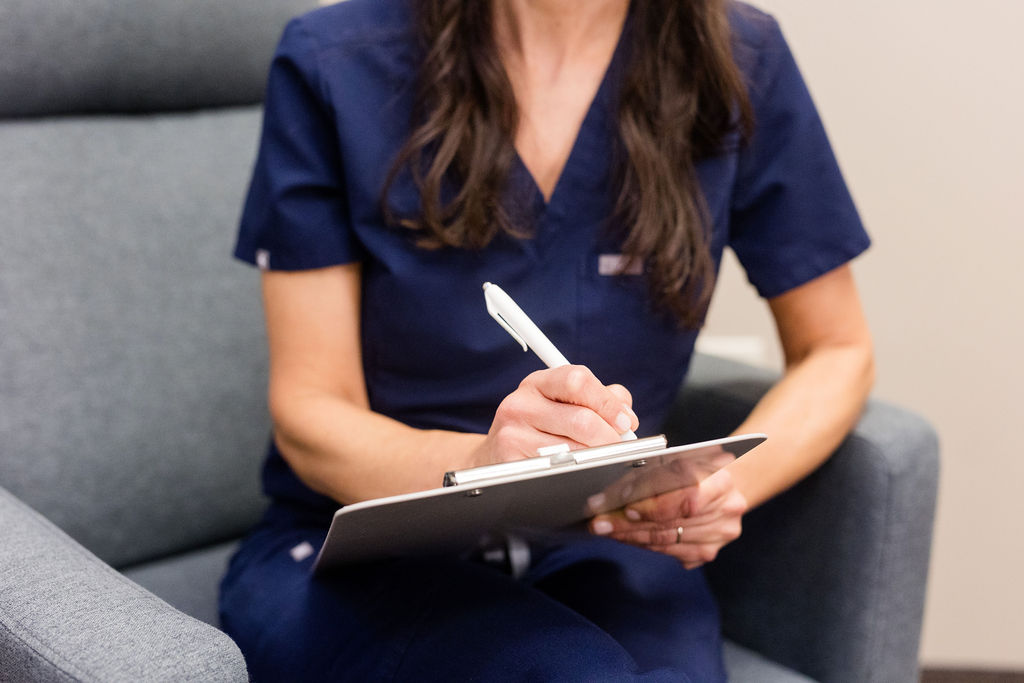 An acupuncturist doing a patient intake and writing notes.